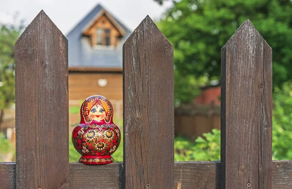 Lalka Matryoshka na drewnianym ogrodzeniu w wiosce. Matryoshka – Rosyjska pamiątkowa pamiątka. — Zdjęcie stockowe