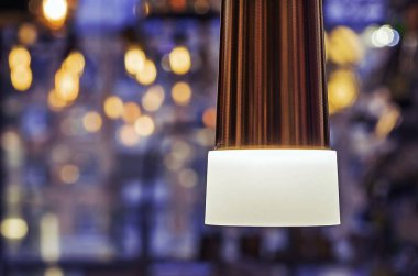 Bokeh ile mavi bir arka plan üzerinde beyaz buzlu cam ile Lamba.