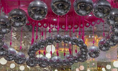 Disko topları pembe iplere tutunur. Disko toplarıyla dolu bir arka plan.