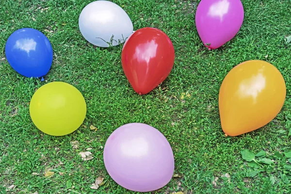 Palloncini multicolori su erba verde. Sfondo di palloncini colorati . — Foto Stock