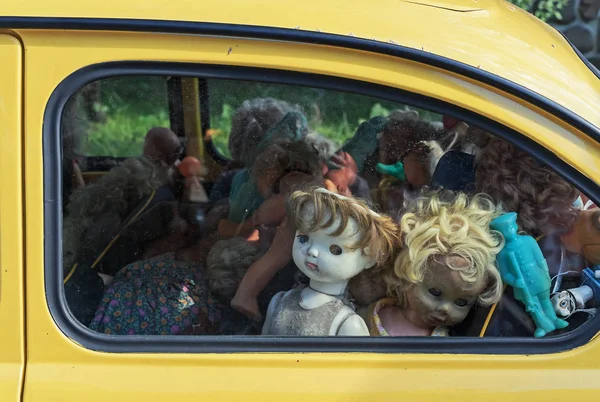 Bir arabanın camının arkasında eski kırık bebekler. Grunge tarzı bebek. — Stok fotoğraf