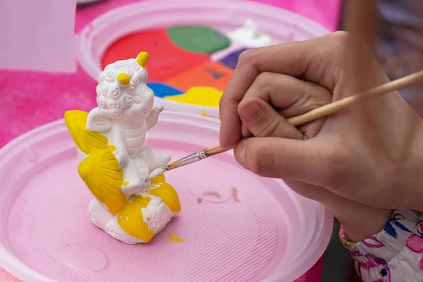 Çocuk parlak renklerle seramik bir heykelcik boyar. Boyama için seramik staruette.
