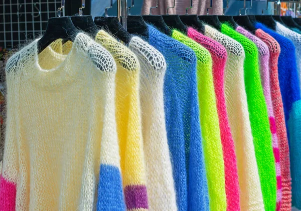Mohair bundy se světlými barvami na věšáky v obchodě. — Stock fotografie
