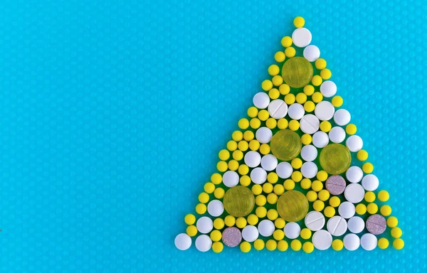 Pillole e vitamine sotto forma di un triangolo su sfondo blu. Concetto medico . — Foto Stock