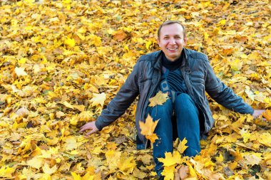 Sonbahar. Parktaki adam sarı yapraklı bir arka planda..