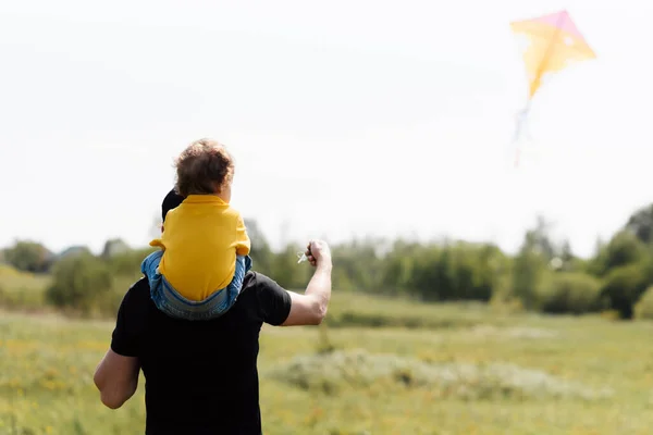 father and son run in the field with a kite
