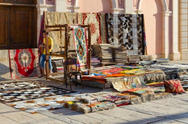 SHARM EL SHEIKH, EGYPT - MAY 12, 2018: Unknown young man sells various colorful oriental carpets on street in business and shopping and entertainment district of Il Mercato in Hadaba
