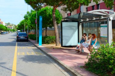 Bir Lloret De Mar, İspanya - 9 Eylül 2018: Bilinmeyen genç kadın şehir otobüs durağı Lloret de Mar, İspanya altındadır