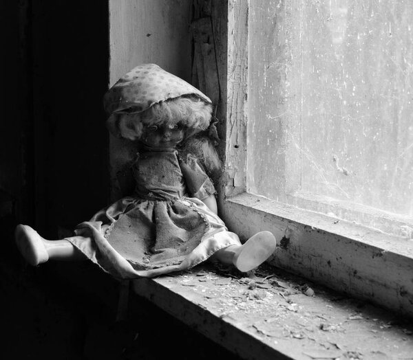 Doll on windowsill in abandoned kindergarten in destroyed village of Kopachi, Chernobyl NPP Exclusion Zone, Ukraine. Black and white image