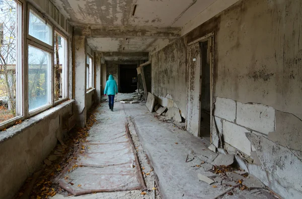 Tourist walks along school corridor in dead abandoned ghost town Pripyat in exclusion zone of Chernobyl nuclear power plant, Ukraine