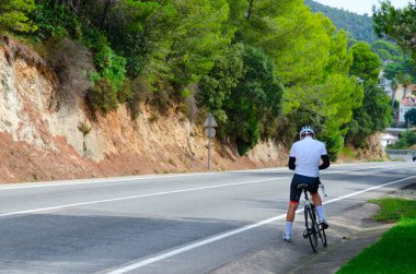 Bir Lloret De Mar, İspanya - 10 Eylül 2018: Lloret de Mar için Tossa de Mar, Costa Brava, Katalonya, İspanya yolun tarafında bilinmeyen bisikletçi değil