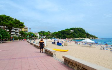 LLORET DE MAR, SPAIN - SEPTEMBER 9, 2018: Unidentified people relax on Fenals Beach in popular resort town of Lloret de Mar, Costa Brava, Catalonia, Spain clipart