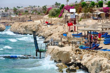 İnsanlar Otel Siva Sharm (eski Savita Resort) 5 *, Sharm El Sheikh, Mısır plajda dinlenme. Sahilde uyarı kırmızı bayrak