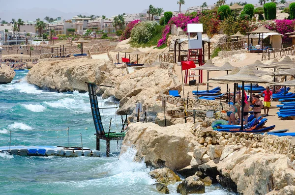People rest on beach of hotel Siva Sharm (ex Savita Resort) 5 *, Sharm El Sheikh, Egypt. Warning red flag on beach — Stock Photo, Image