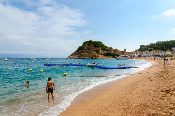 Menschen entspannen sich am Strand in beliebten Ferienort tossa de mar, costa brava, Katalonien, Spanien. schöner Blick auf die alte Stadtfestung — Stockfoto