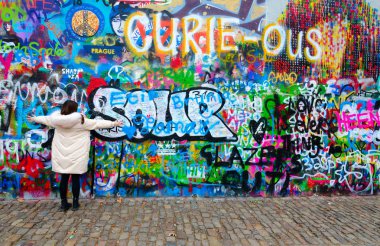 Tourist is located at famous wall of John Lennon in Prague, Czech Republic clipart