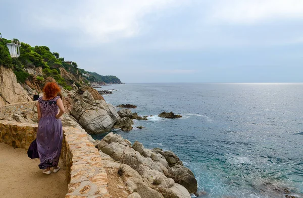 Mujer admira hermosa vista de la costa rocosa en Lloret de Mar, Costa Brava, Cataluña, España —  Fotos de Stock