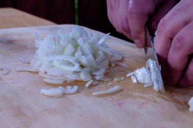 Aşçı soğanları bıçakla keser..