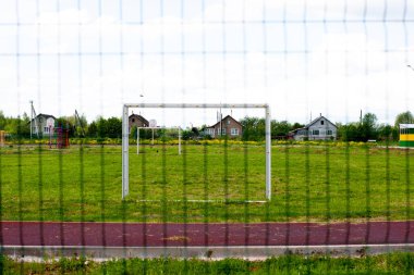 Futbol sahası. Sahada yeşil doğal çimenler. Geçit ızgarasından