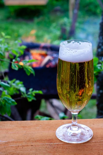 暖かい夜に冷たいビールとガラス グリルで焼ける火を背景にしたビール — ストック写真