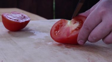 Büyük bir domatesi bıçakla dilimlemek. Yemek hazırlama. sebze