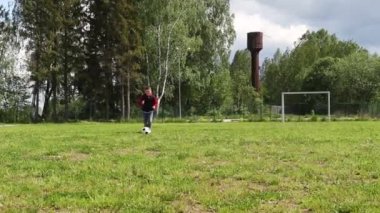Bir çocuk futbol oynuyor. Topu kaleye doğru itiyor.
