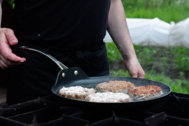 Aşçı pirzolaları ateşte tavada kızartıyor. Doğadaki ızgarada yemek. piknik.