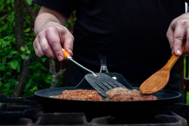 Aşçı pirzolaları ateşte tavada kızartıyor. Doğadaki ızgarada yemek. piknik.