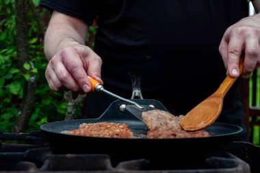 Aşçı pirzolaları ateşte tavada kızartıyor. Doğadaki ızgarada yemek. piknik.