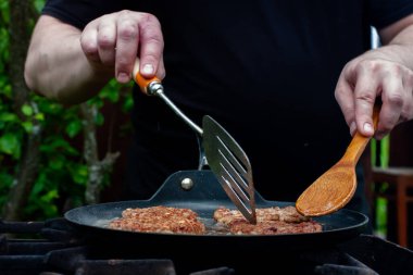 Aşçı pirzolaları ateşte tavada kızartıyor. Doğadaki ızgarada yemek. piknik.