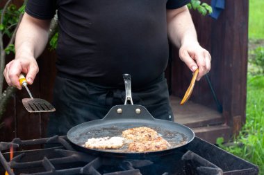 Aşçı pirzolaları ateşte tavada kızartıyor. Doğadaki ızgarada yemek. piknik.