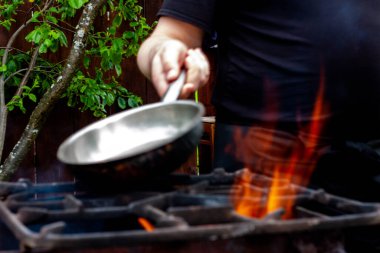 Aşçı tavayı ateşin üstünde ısıtır. Mutfak ızgarada.