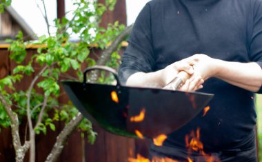 Aşçı sebzeleri karıştırıp tavaya atıyor. Tavada yemek pişirmek