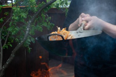 Aşçı sebzeleri karıştırıp tavaya atıyor. Tavada yemek pişirmek