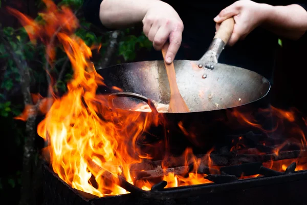 料理人は大きな明るい火の上で料理をローストします — ストック写真