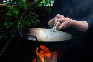 Aşçı sebzeleri karıştırıp tavaya atıyor. Tavada yemek pişirmek