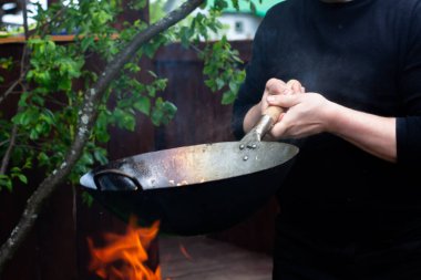 Aşçı soğan, havuç ve tavukla ahşap bir spatulayı karıştırır.