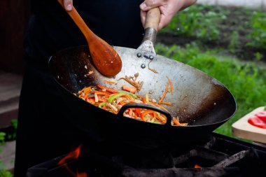 Aşçı, ateşte tavukla sebzeleri karıştırır. Asya mutfağı