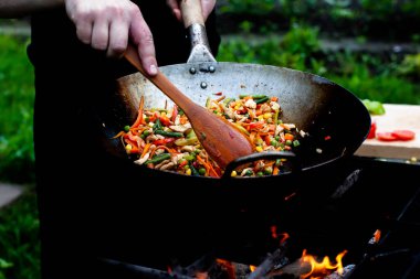 Aşçı, ateşte tavukla sebzeleri karıştırır. Asya mutfağı