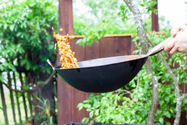 Aşçı sebzeleri karıştırıp tavaya atıyor. Tavada yemek pişirmek