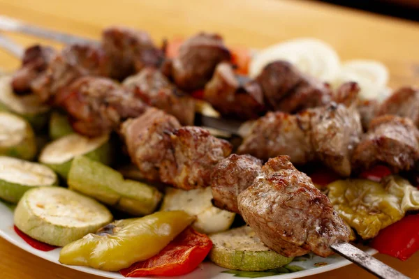 Izgara sebzelerin üzerine otlar serpiştirilmiş et dolu bir tepsi.