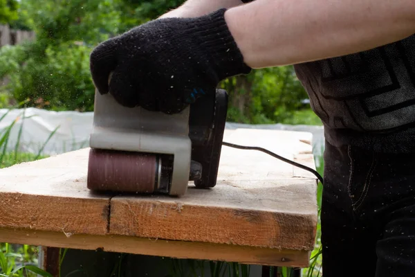 一个戴黑色手套的男人用砂子磨碎木板 木制品 — 图库照片