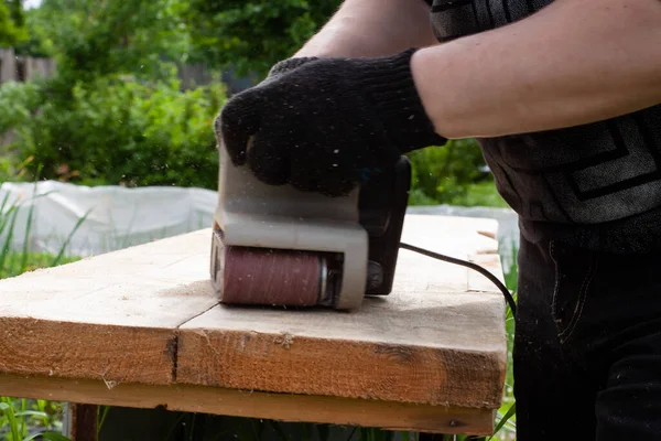 一个戴黑色手套的男人用砂子磨碎木板 木制品 — 图库照片