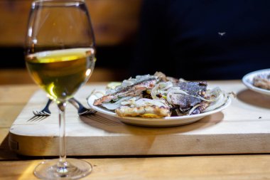 Limonlu kırmızı balık dilimleri bir bardak beyaz şarapla süslenmiş yeşillikler.