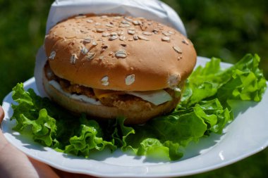Marulun üzerinde sulu bir hamburger tabağı. Fast food posteri