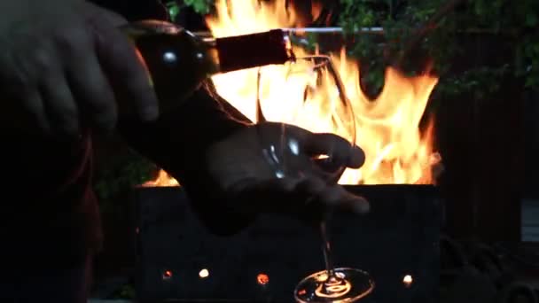 Молодий Чоловік Наливає Вино Склянку Тлі Палаючого Вогню Грилі — стокове відео