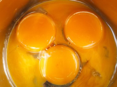 Bir kasede üç yumurta sarısı. Kahvaltı pişir. Sarıdan yapılmış bir gülümseme..