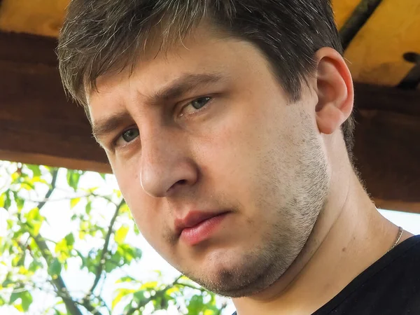 Yüzü tıraşsız, yakışıklı, ciddi bir adamın portresi.