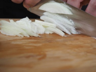 Aşçı ahşap bir tahtada soğan kesiyor. poster.