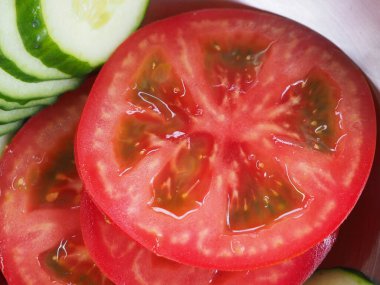 Salatalık ve domatesler tahta bir tahtanın üzerinde daireler çiziyor. sebze kullanımı